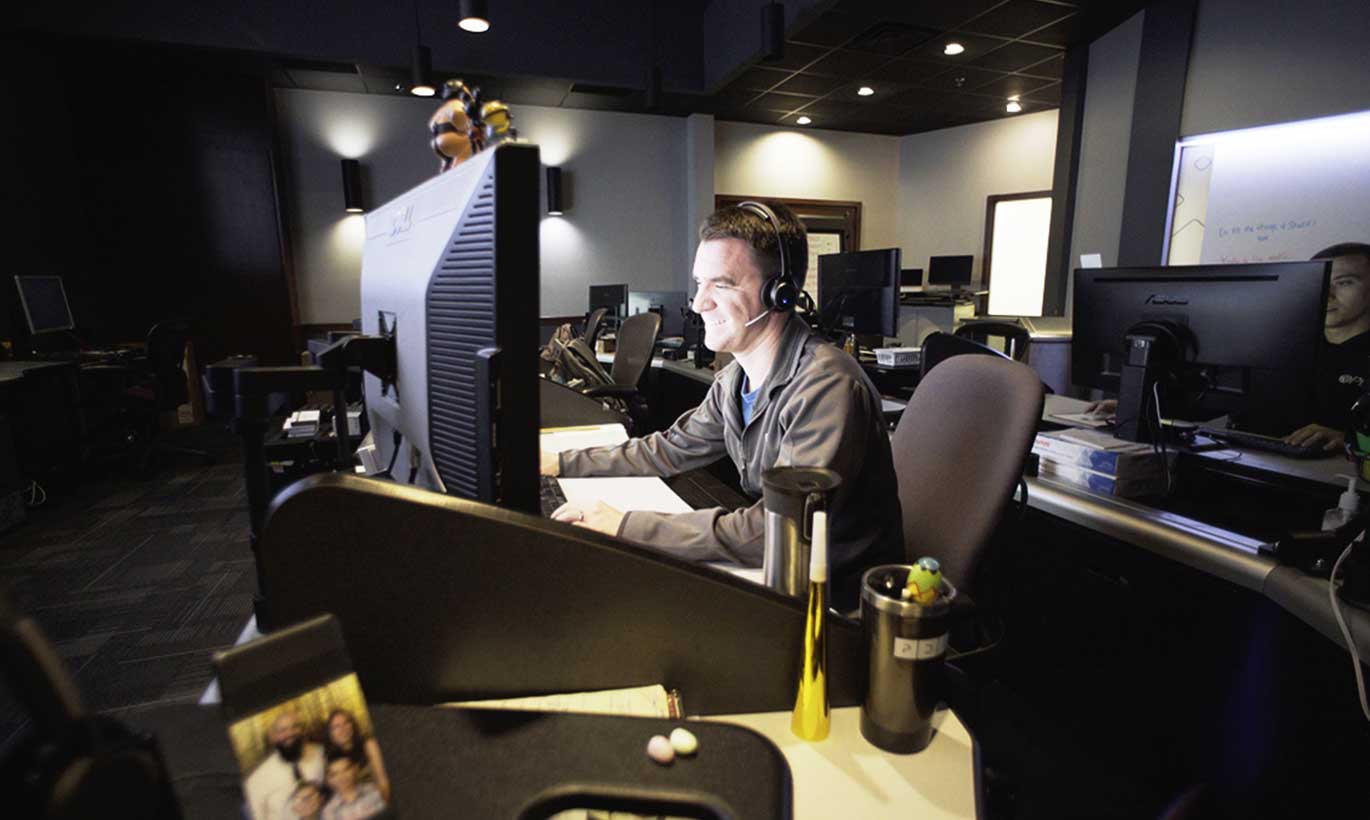 A man works in a dimly-lit room on his computer in Temple, Texas