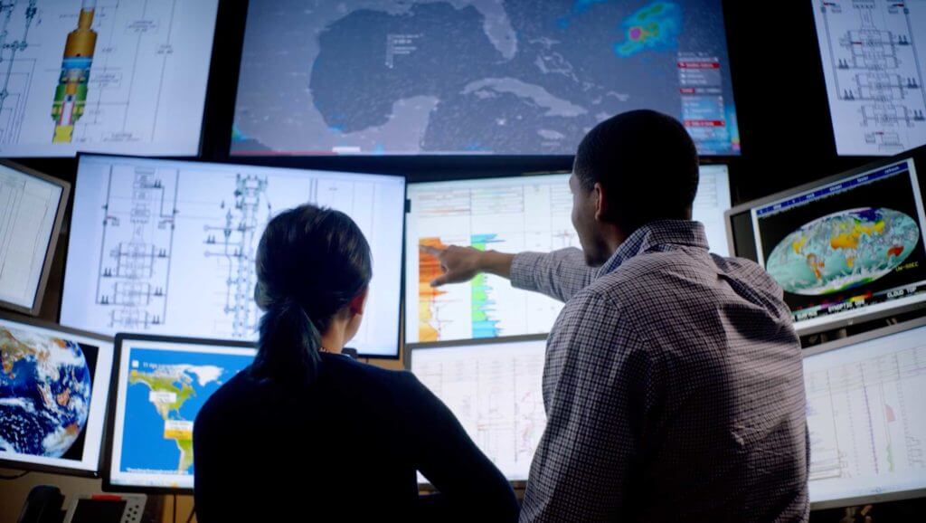 A man and woman point out important data and statistics on energy graphs and maps in Houston, Texas
