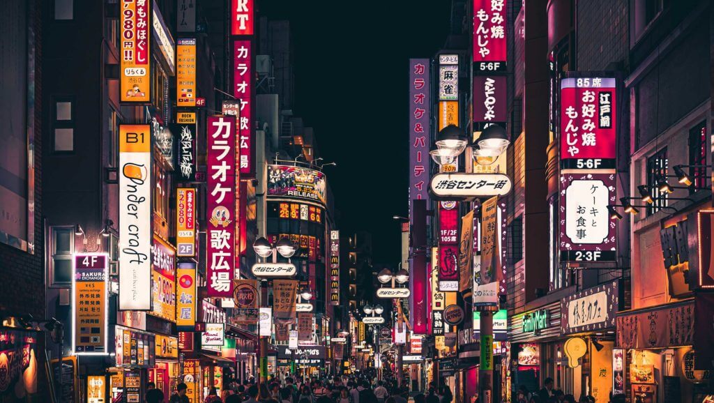 Neon street signs cover the walls of building in Tokyo, Japan at night
