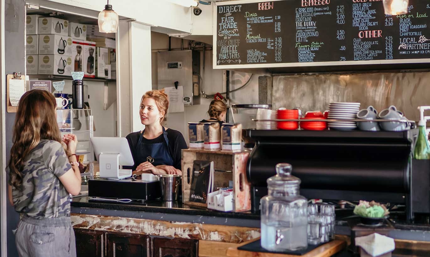 A barista takes a woman's order in a coffeeshop.