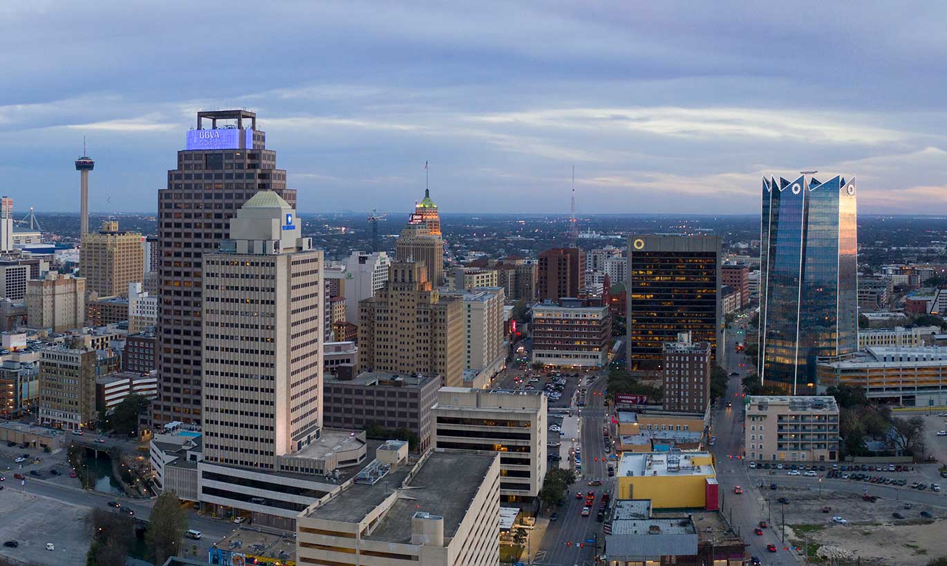 The San Antonio, Texas skyline at dusk features many tall buildings made of glass and concrete.