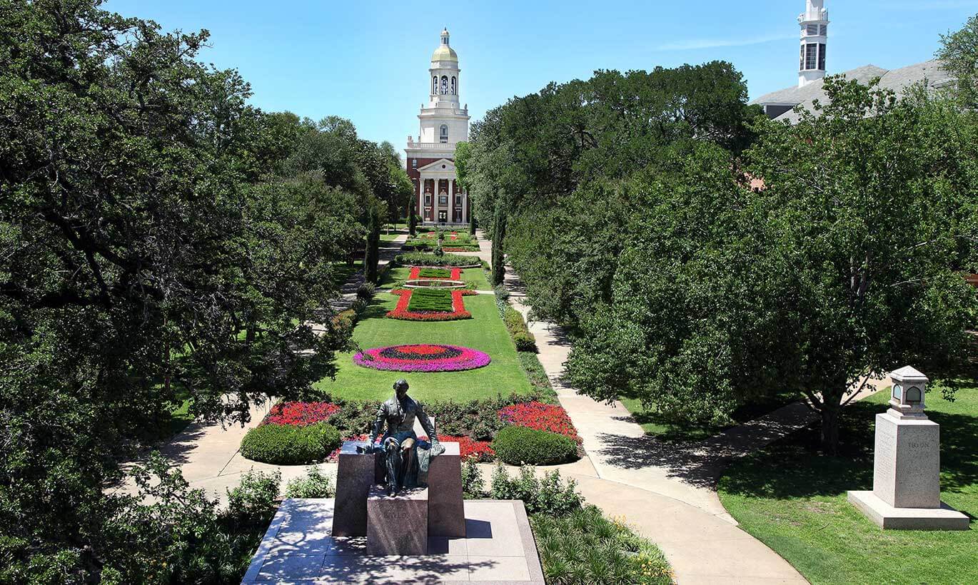 A green lawn with colorful flowers sits in front of Pat Neff Hall at Baylor University in Waco, Texas.