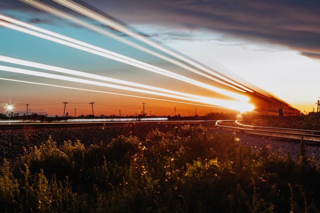 A train moves past very quickly on railroad tracks, leaving light trails in Abilene, Texas