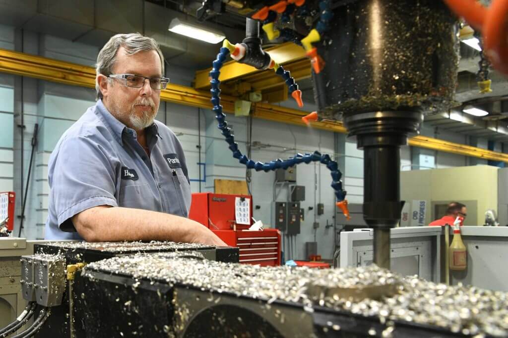 A man wearing glasses works with industrial machinery at Pantex.