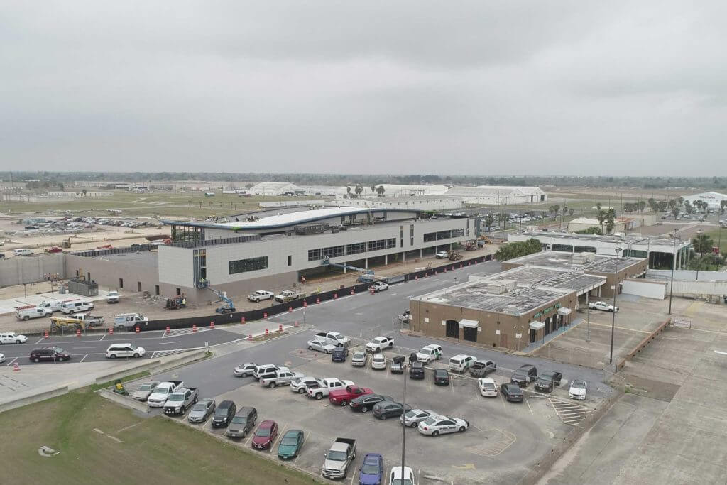 Cars are parked in the parking lot of an airport construction site in Brownsville, Texas.