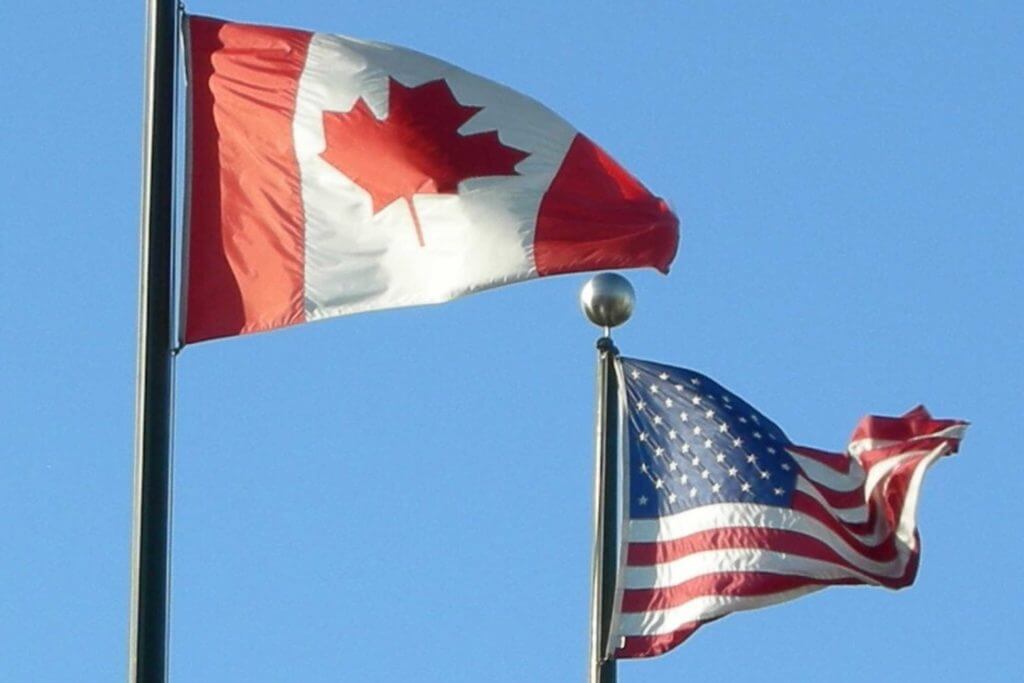 The US and Canadian flag raised on flagpoles