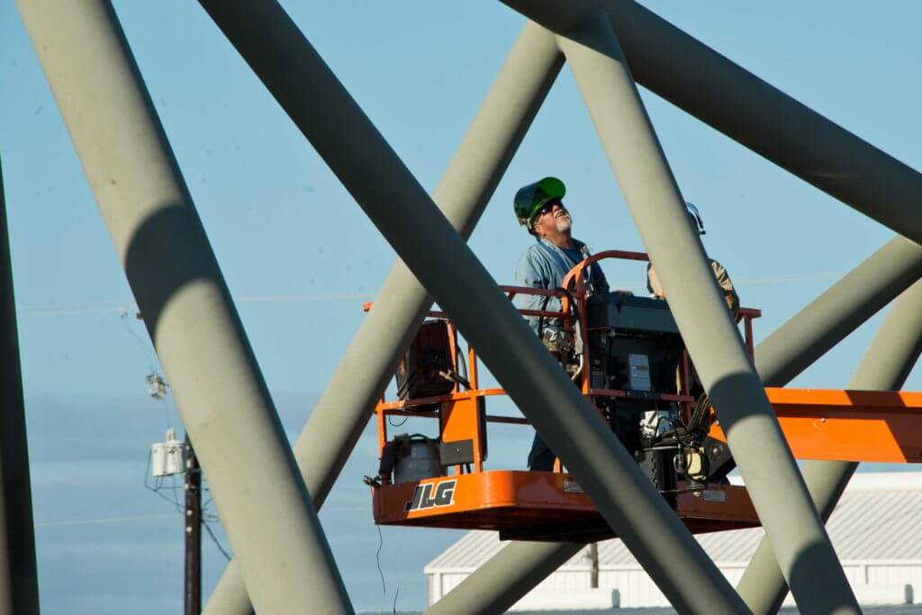 A man standing on a cherry picker platform working on a construction site in Corpus Christi, Texas