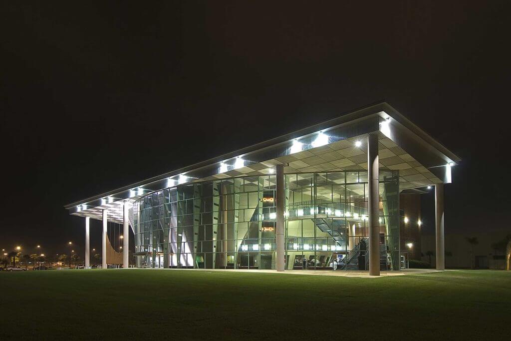 A modern building with clear glass panels lit up at night at Texas A&M University