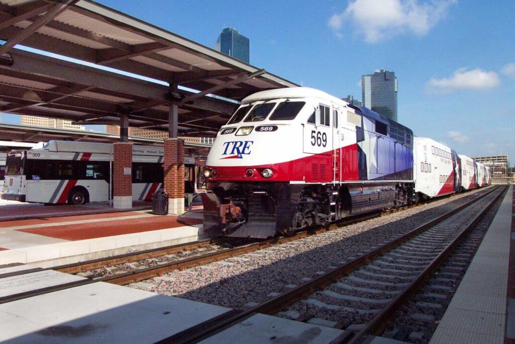 A red and white passenger train pulls into a railway station.