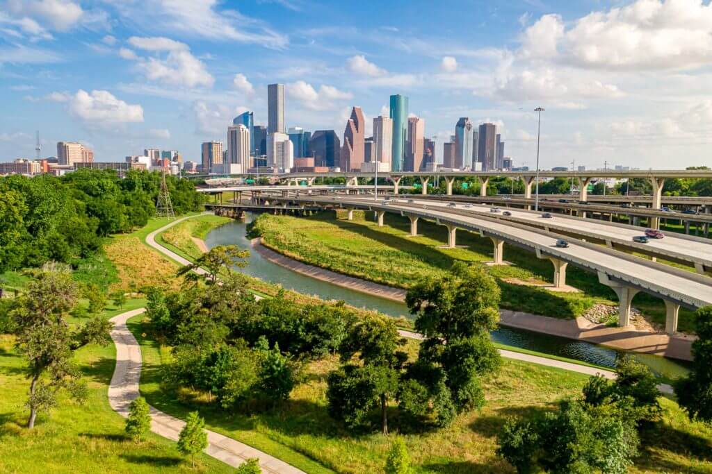 Aerial view of downtown Houston, Texas, with Buffalo Bayou Park and Memorial Drive in the foreground