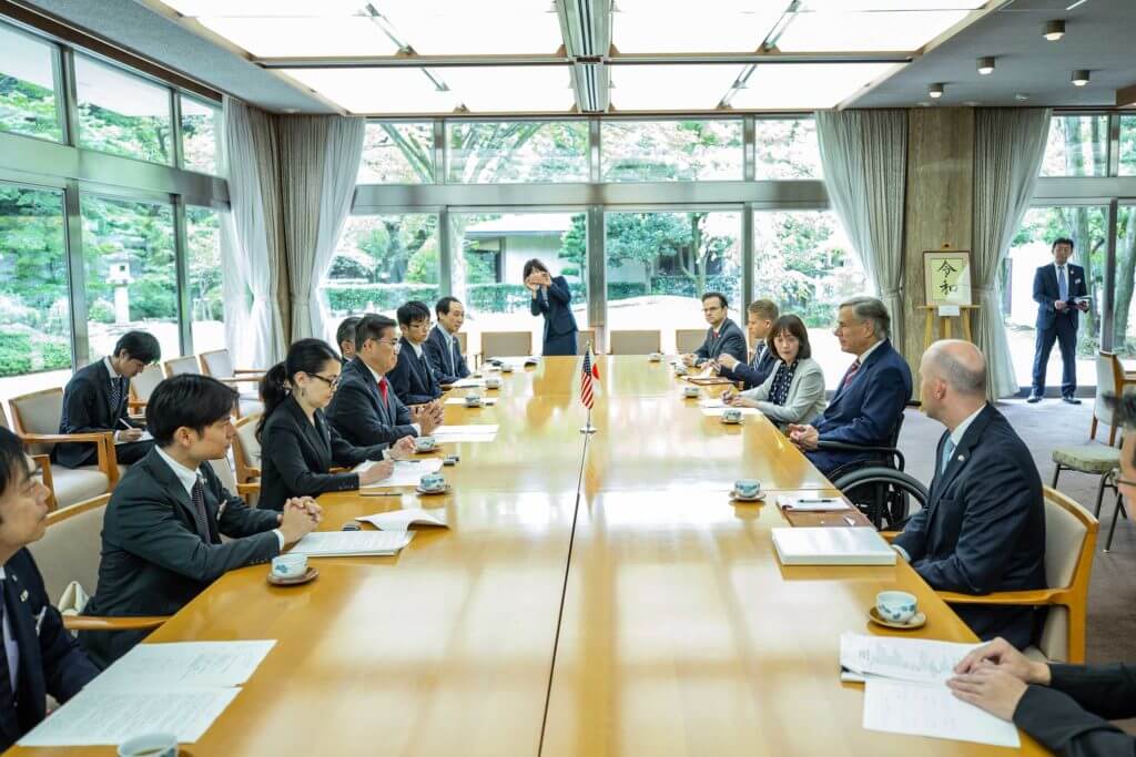 A group of consulates and international business people sit together at a large conference table