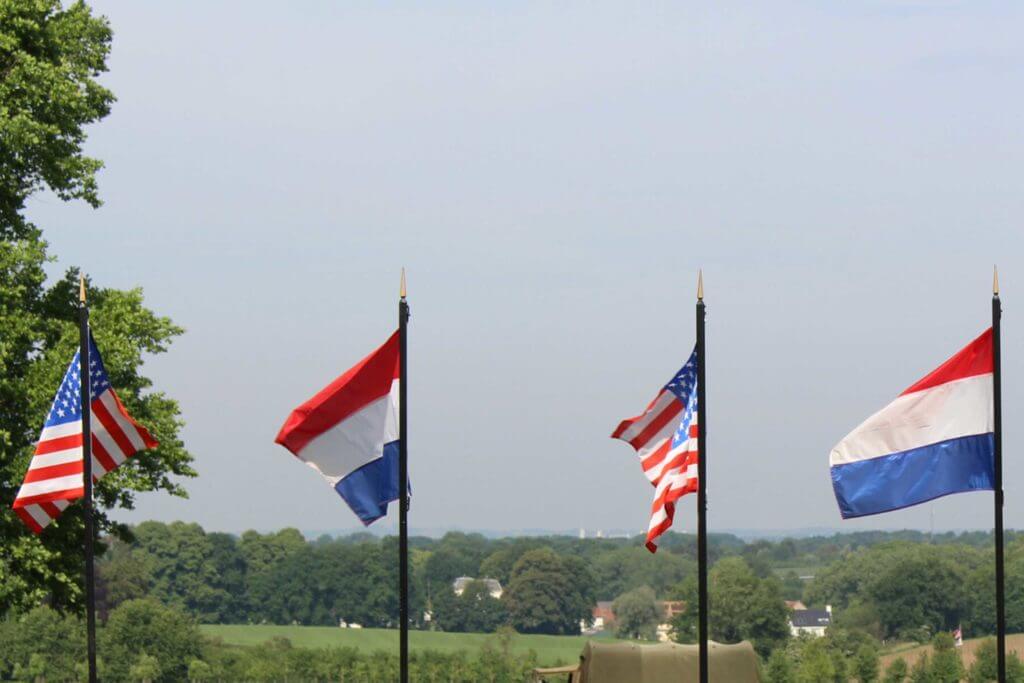 The flags from the US and the Netherlands are raised on tall poles