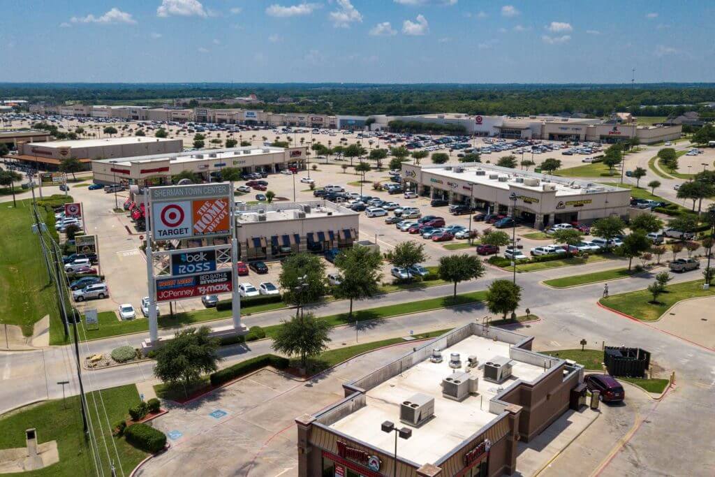 Aerial view of the Town Center in Sherman, Texas with shops and a large parking lot.