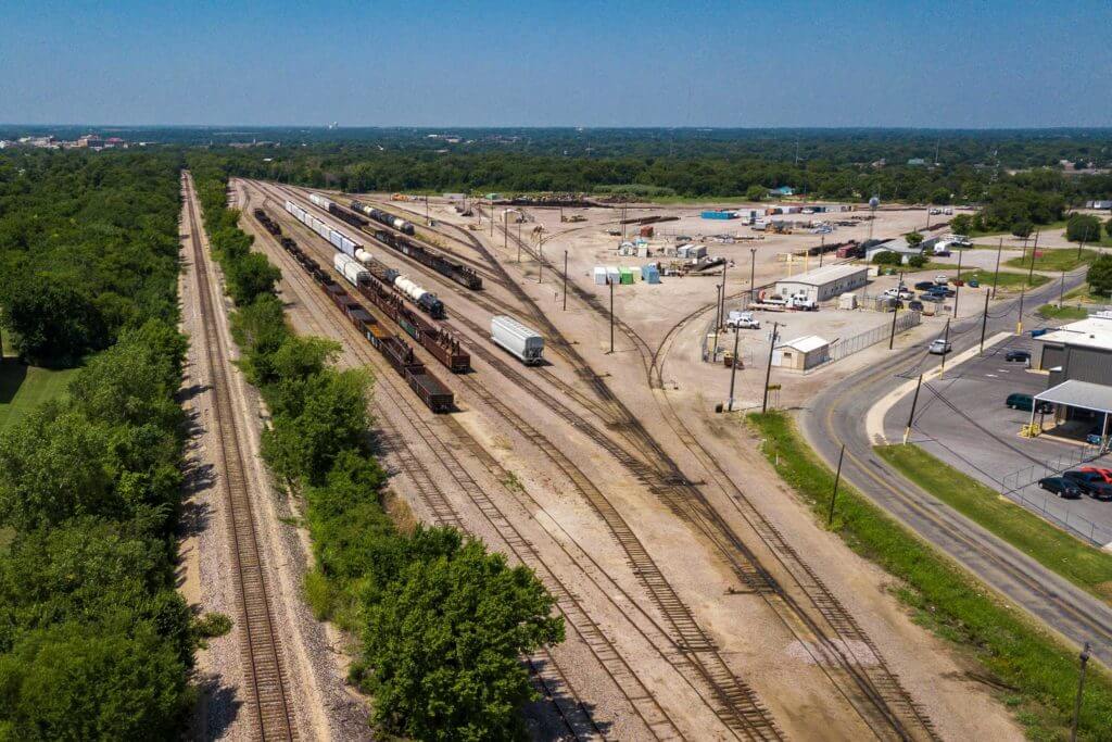 Three trains transport goods down the main railway lines in Sherman, Texas.