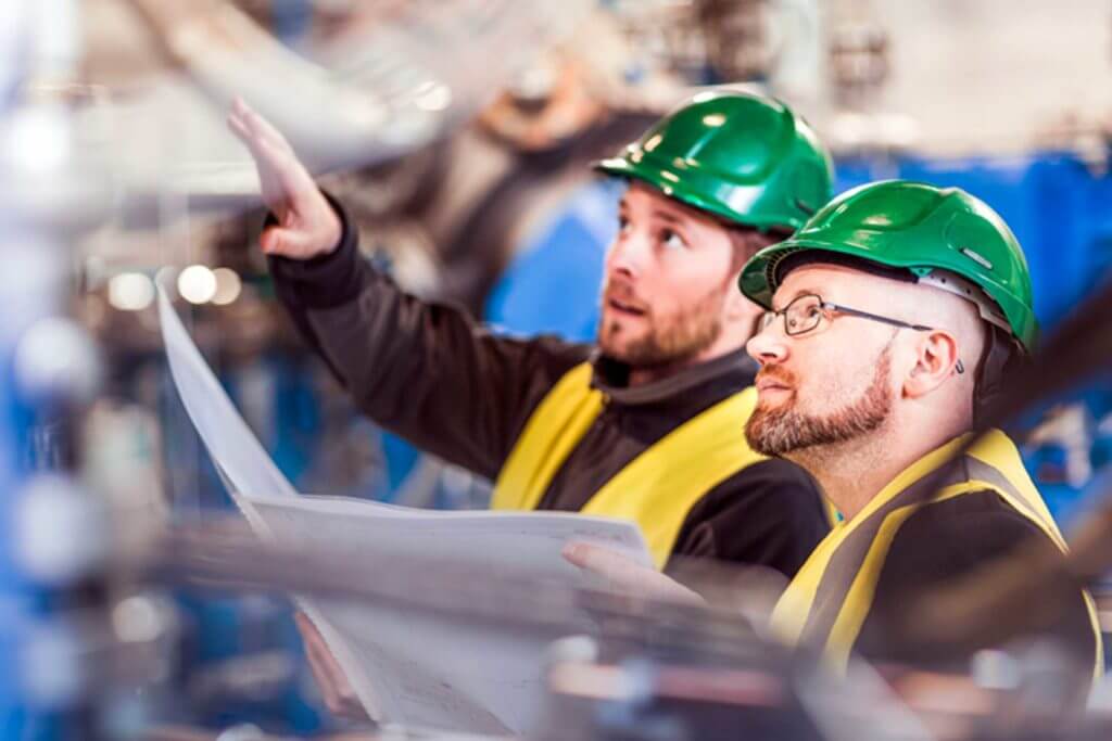 Two men in hard hats discuss their work plan.