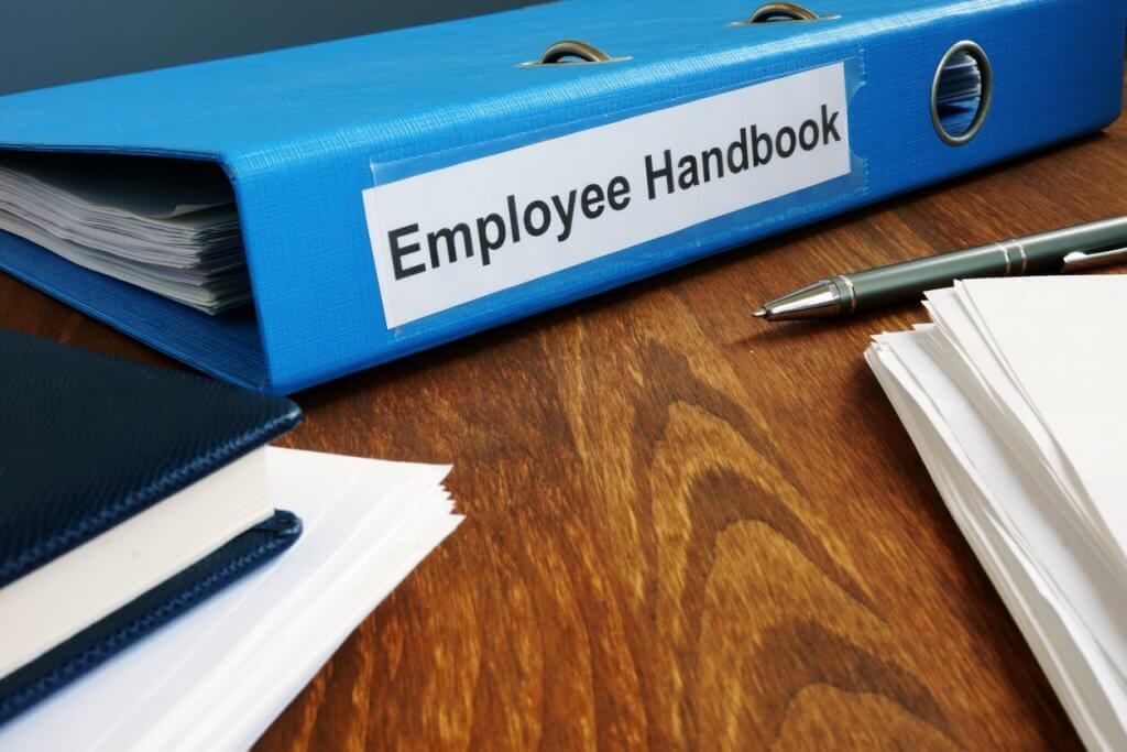 Employee handbook manual in folder and documents on a wooden table
