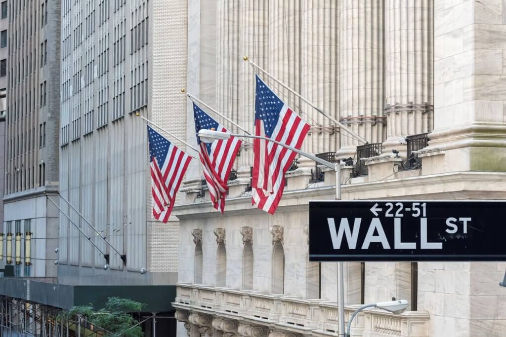 Wall street sign in New York City with New York Stock Exchange in the background
