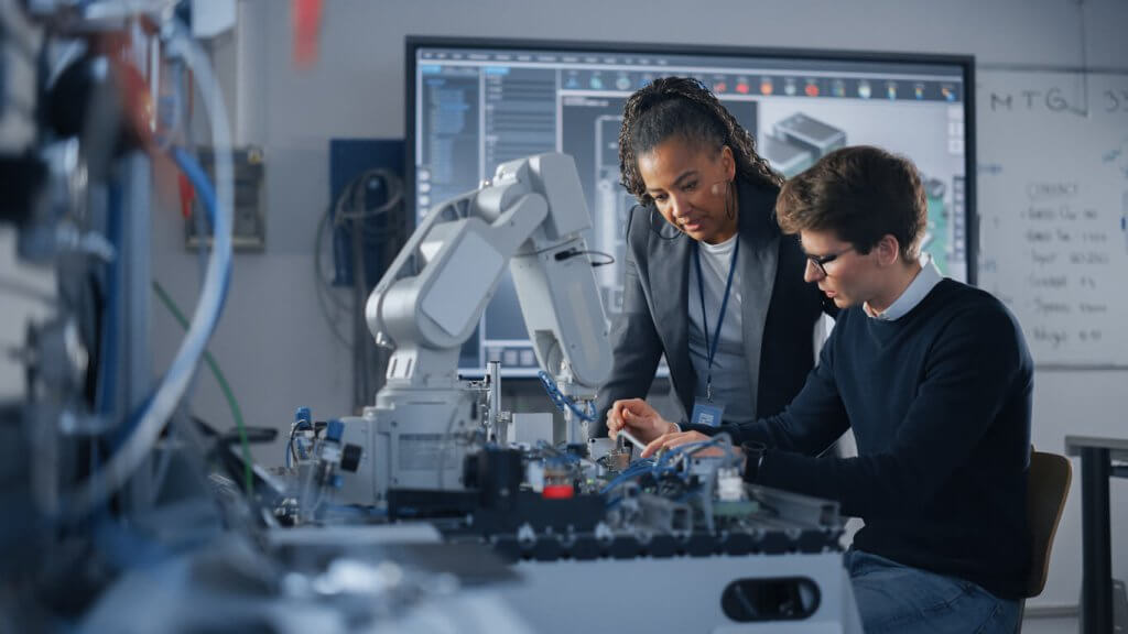 Male student engineer discussing ideas with teacher while working on computer process as he is working on his career and technical education