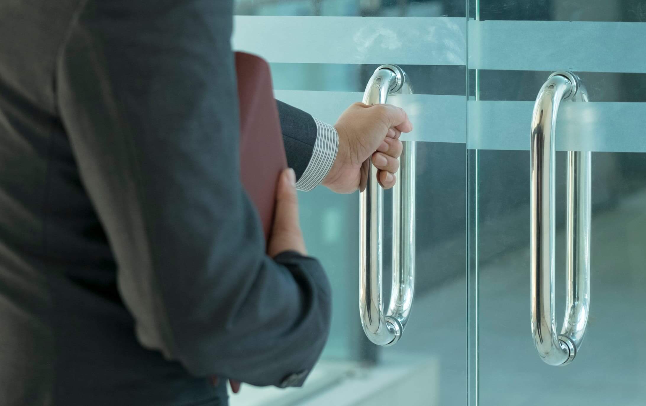 Businessman entering an office by opening out a glass door