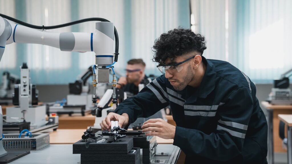 Student engineer Assembling Robotic Arm with computer in Technology Workshop